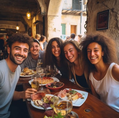 A group of friends gathered around a table, sharing food and drinks, enjoying each other's company in a lively restaurant setting