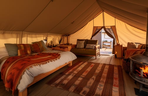 A cozy tent featuring a bed and a fireplace, creating a warm and inviting atmosphere for relaxation. A cozy tent featuring a bed and a fireplace, creating a warm and inviting atmosphere for relaxation.