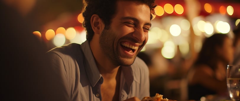 a man smiling and laughing while eating food a man smiling and laughing while eating food