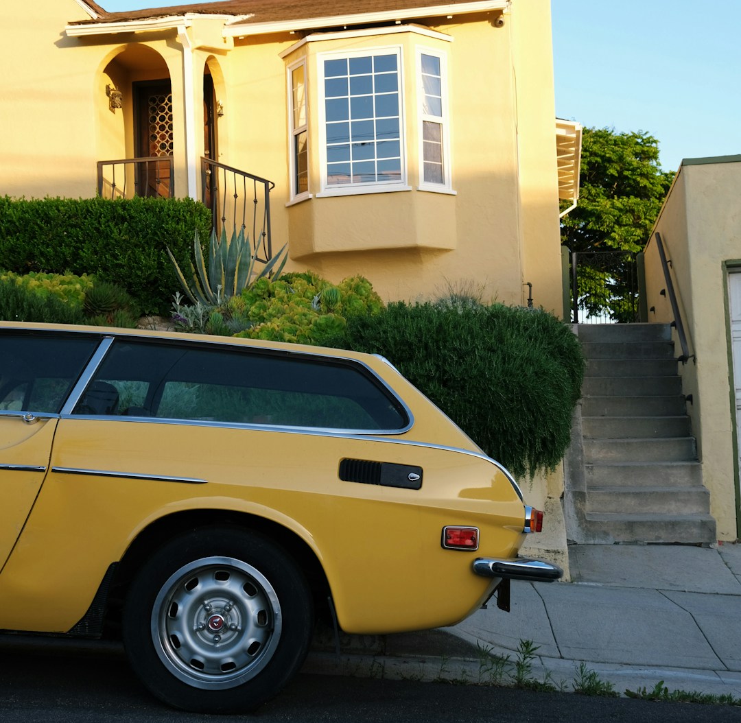 A yellow car parked in front of a house A yellow car parked in front of a house