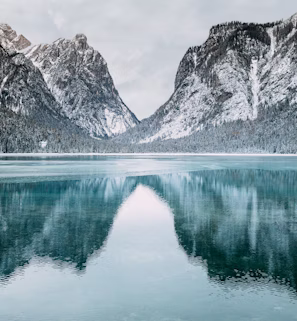 body of water and snow-covered mountains during daytime body of water and snow-covered mountains during daytime