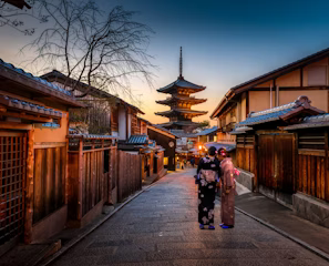 two women in purple and pink kimono standing on street two women in purple and pink kimono standing on street