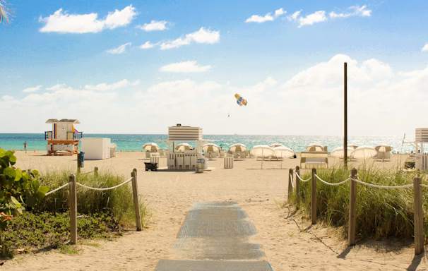 gray pathway leading to parasol, lifeguard house, and sea a daytime gray pathway leading to parasol, lifeguard house, and sea a daytime