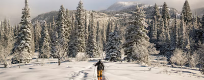 man in black and orange outfit walking on snow man in black and orange outfit walking on snow