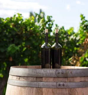 two black glass bottles on the top of the brown wooden barrel two black glass bottles on the top of the brown wooden barrel