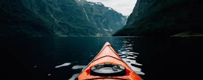 orange canoe on lake surrounding with mountain at daytime
