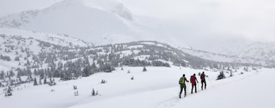 three people walking on snow three people walking on snow