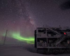 white multi-storey building under starry night and northern lights white multi-storey building under starry night and northern lights