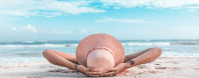 woman in brown sun hat lying on sand during daytime woman in brown sun hat lying on sand during daytime