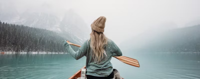 woman in gray long sleeve shirt sitting on brown wooden boat on body of water during woman in gray long sleeve shirt sitting on brown wooden boat on body of water during