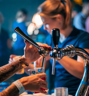 a group of people standing around a bar a group of people standing around a bar