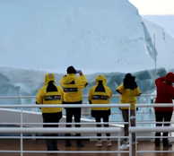 a group of people in yellow jackets standing on a boat a group of people in yellow jackets standing on a boat
