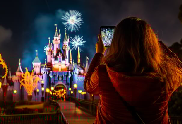 woman recording the fireworks above a famous theme park in Orlando, Florida