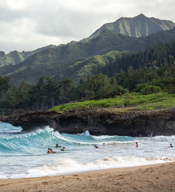 people swimming near shore with waves during daytime