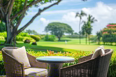 Two wicker chairs and a small table set on a grassy area, creating a cozy outdoor seating arrangement.