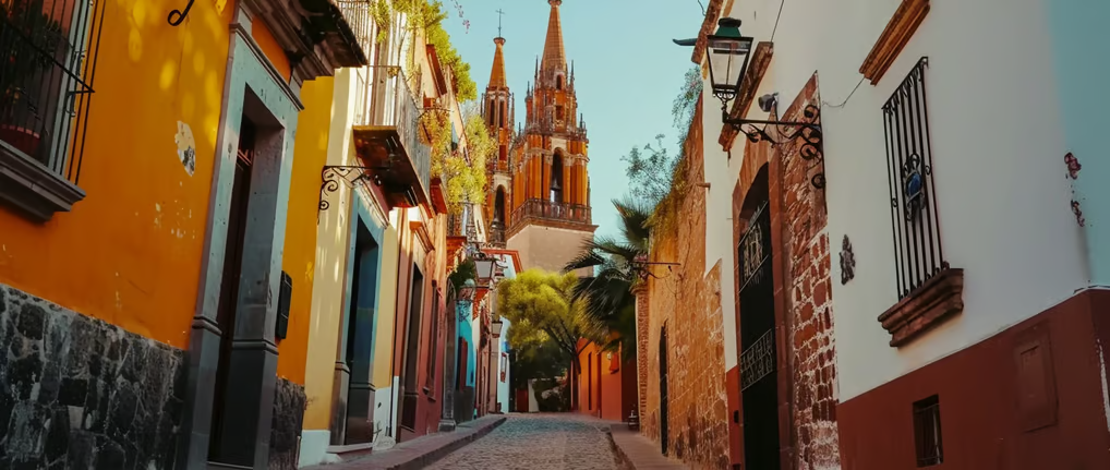 a narrow street with a church steeple in mexico