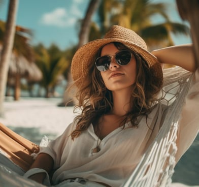 a woman in a straw hat and sunglasses sitting in a hammock in Tulum beach in Mexico