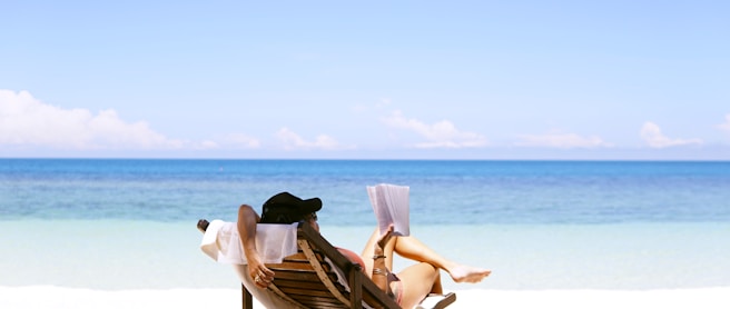 woman sits on brown wooden beach chair