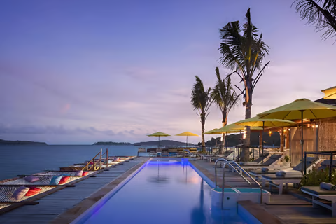 A pool in koh kong, cambodia with lounge chairs and umbrellas A pool in koh kong, cambodia with lounge chairs and umbrellas