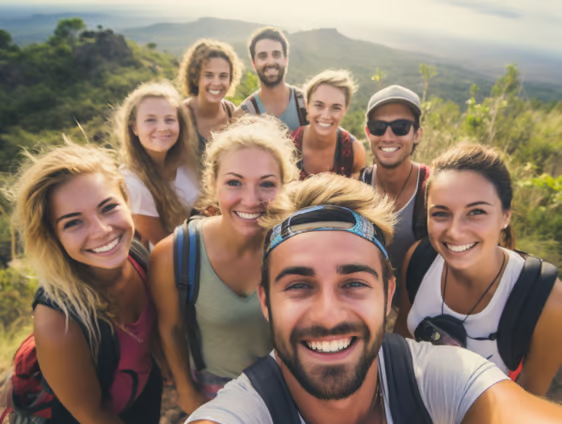 a group of travellers standing around a man taking a selfie a group of travellers standing around a man taking a selfie