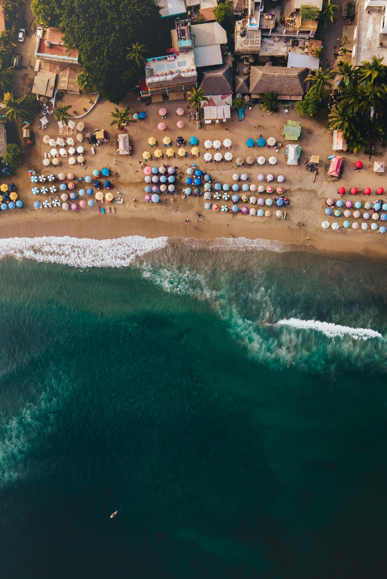 Aerial view of playa bucerias featuring colorful umbrellas and lounge chairs arranged along the sandy shore